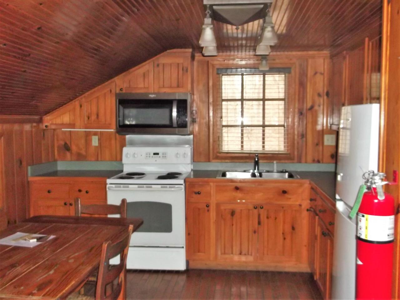 A view of the kitchen in cabin 11 including a fridge, oven, microwave, double sink and dining area